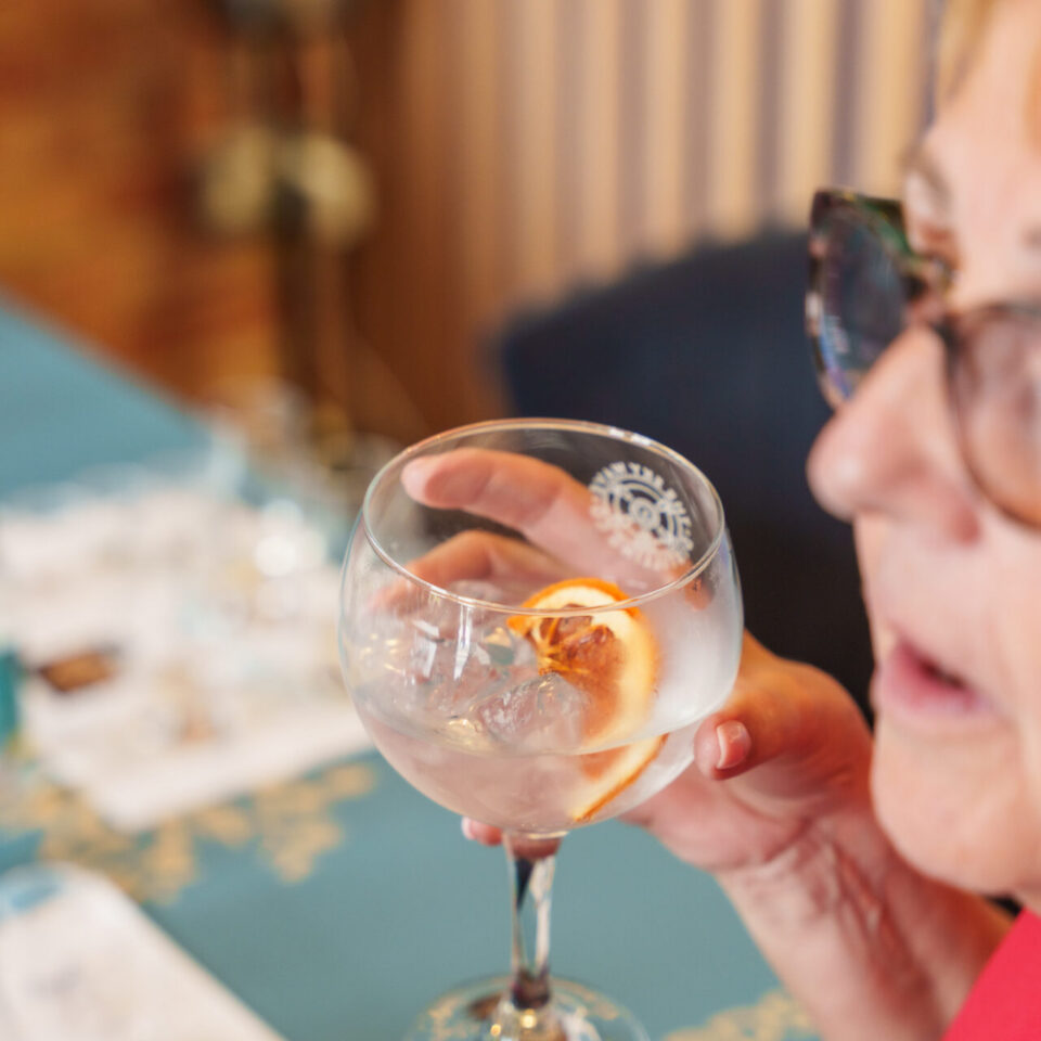 A resident raising a glass of Golden Hour gin and tonic