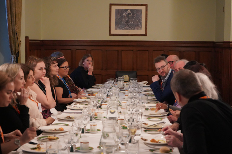 Delegates seated along the table beneath two annunciator screens