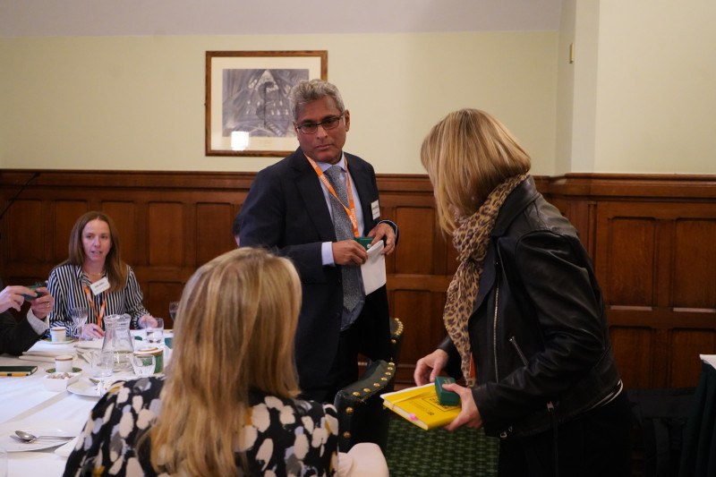 Two delegates exchanging a document at the head of the table